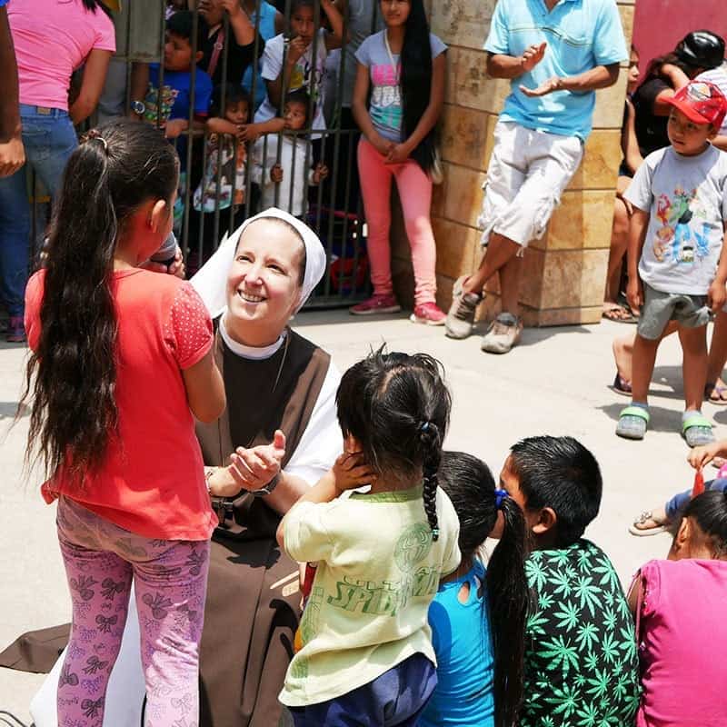 Sr. Eva kniend vor Kindern