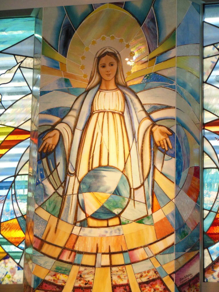 Es zeigt die Jungfrau Maria als Gnadenvermittlerin mit ausgestreckten Händen und vor ihr die Weltkugel.