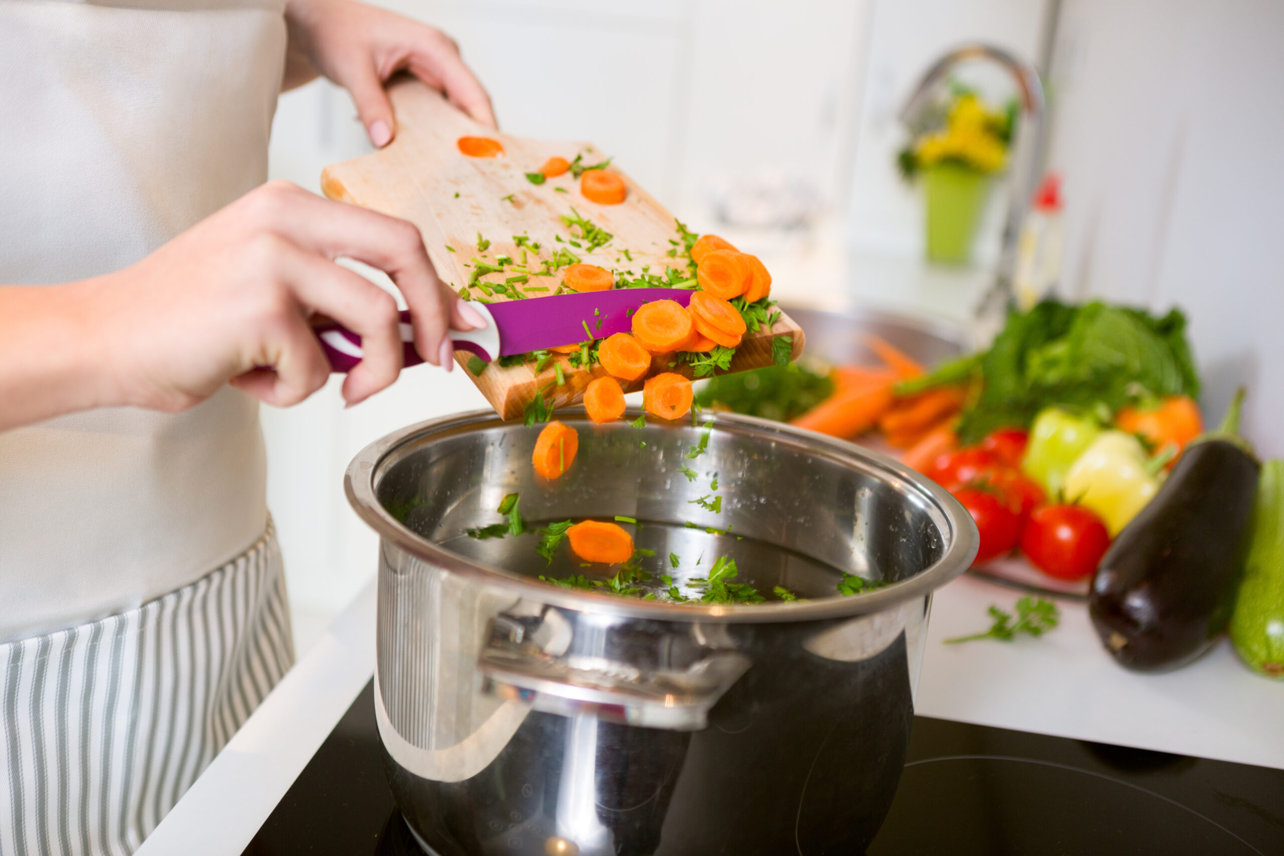 Fresh vegetables on the cutting board are falling in the pot, concept of cooking
