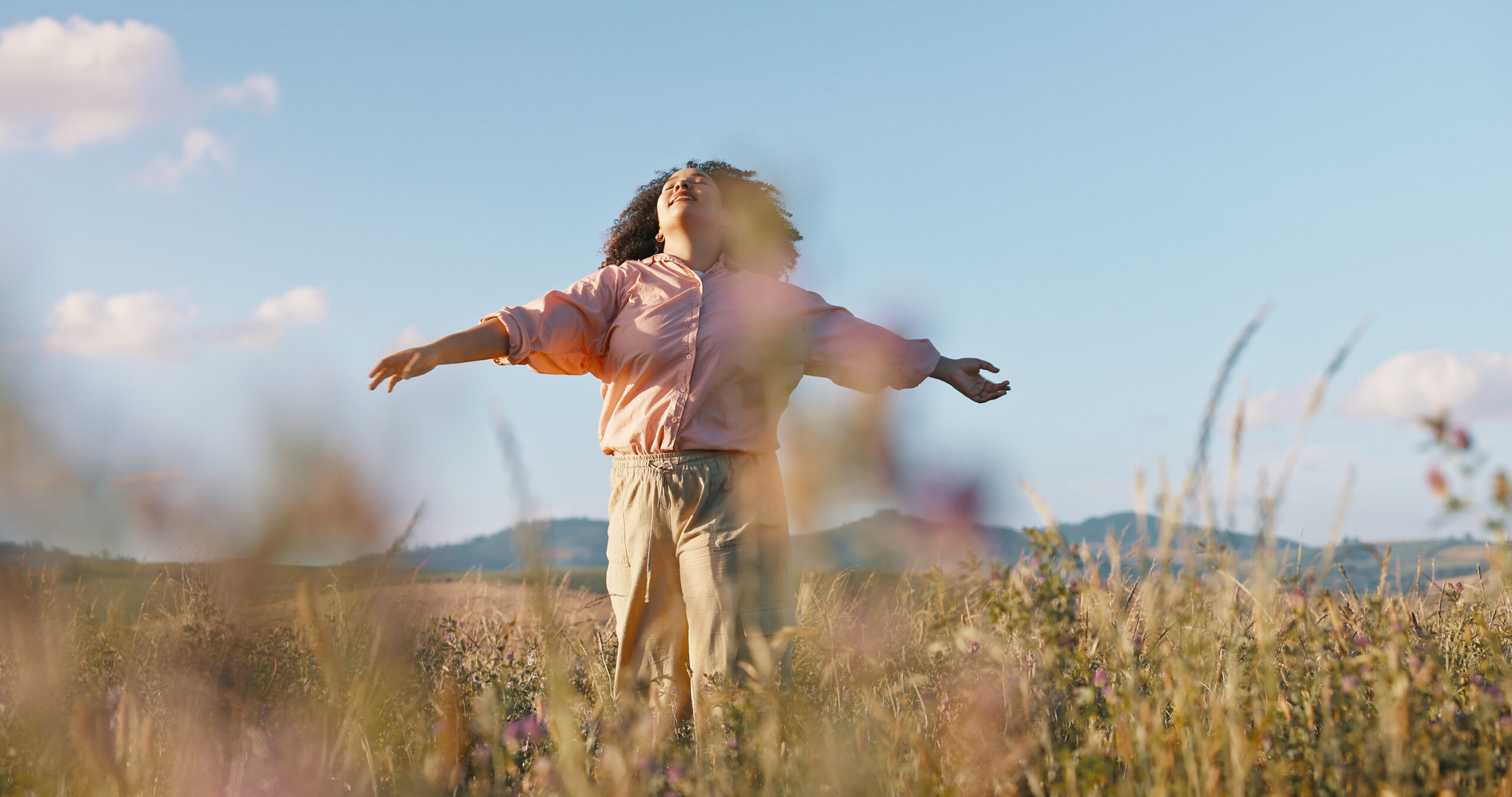 Woman, freedom and dancing in field of flowers, countryside and peace in sustainable environment. Female person, holiday and adventure in nature or outdoors, calm and zen or wellness on vacation.
