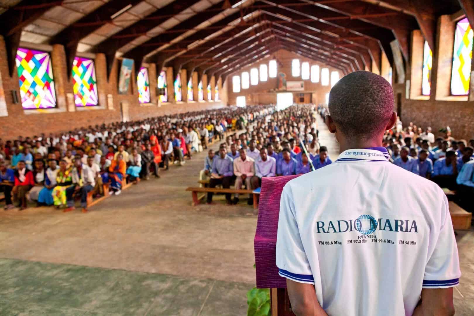 Mann in Ruanda mit einem Radio Maria - T-Shirt in einer vollen Kirche